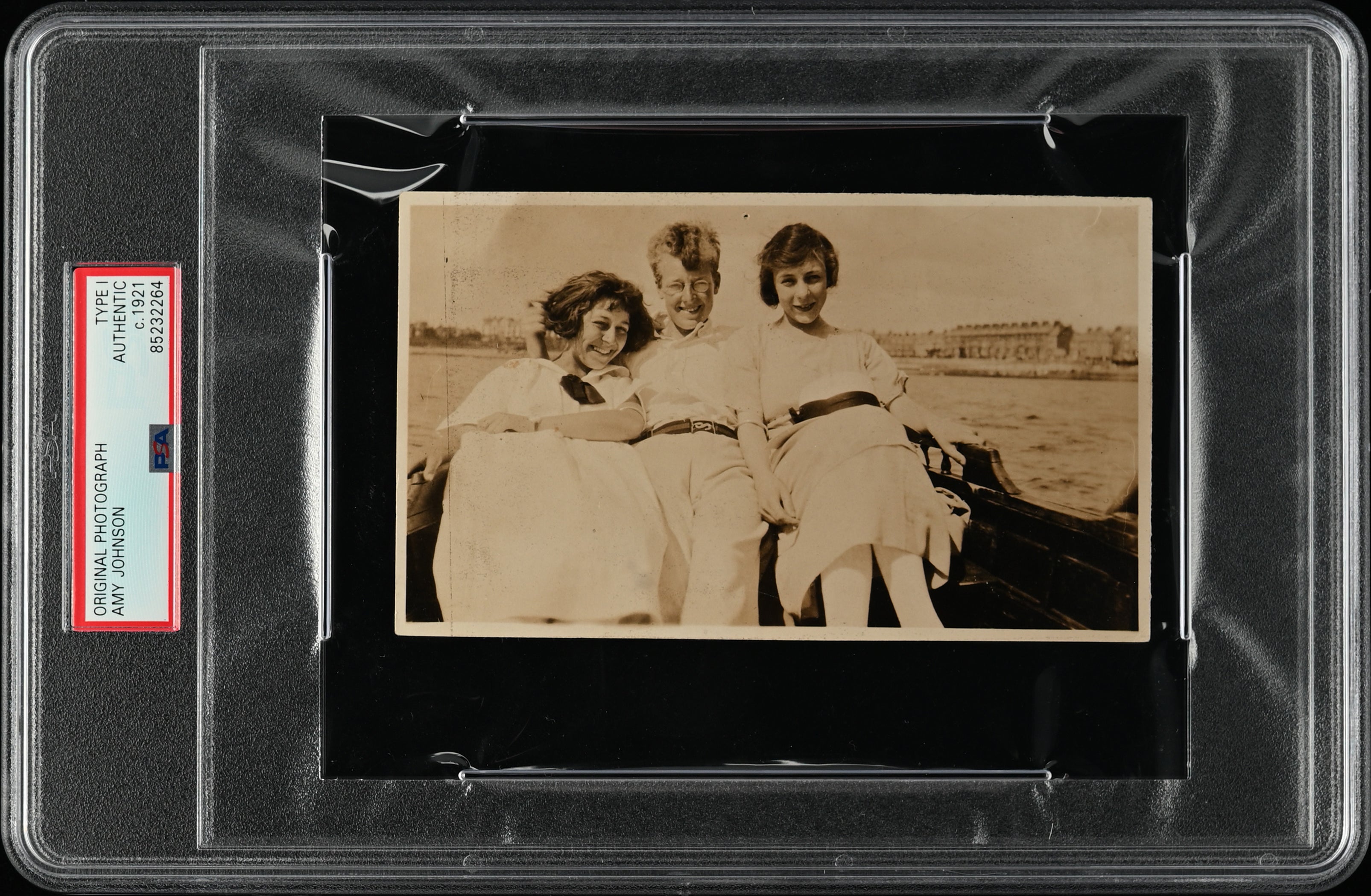 PSA/DNA encapsulated original photograph of pioneering aviator Amy Johnson seated with companions, circa 1921.